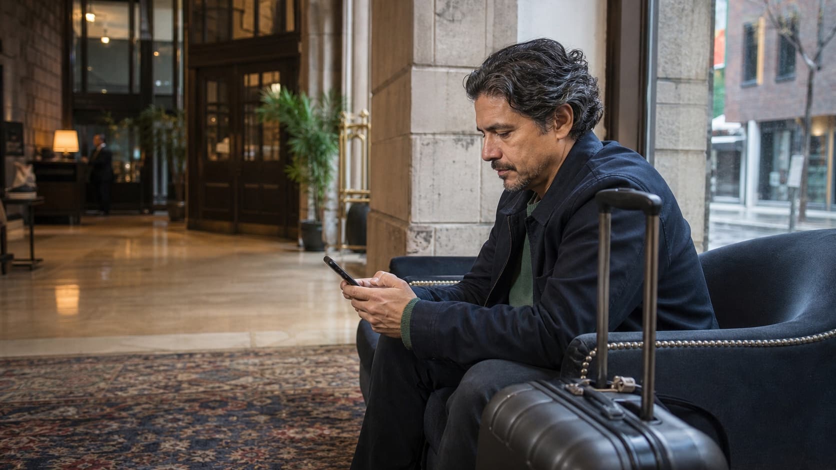 Voyageur adulte avec ses bagages utilisant un téléphone dans le hall lumineux d’un hôtel au Québec