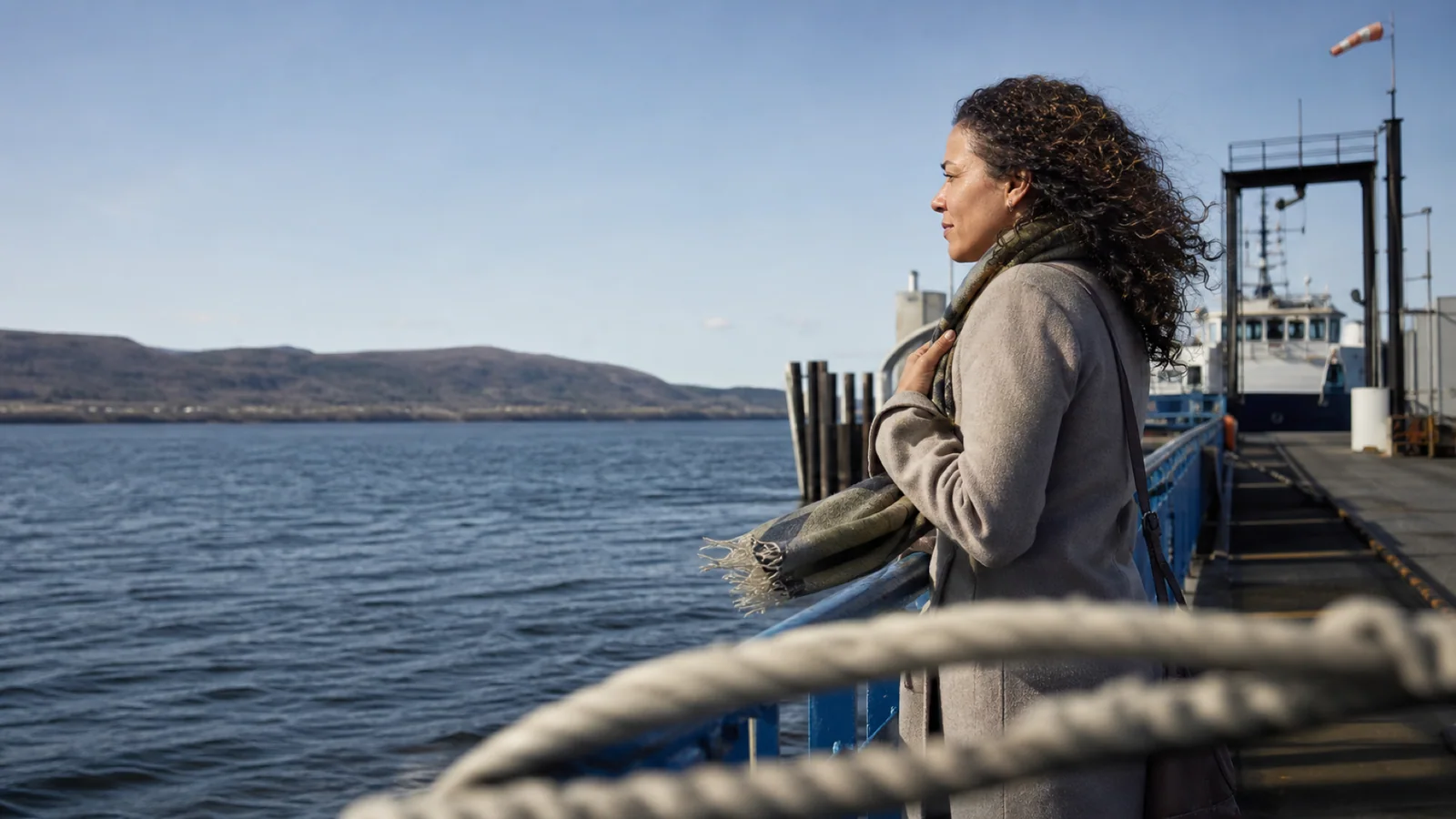 A woman waits for a regional ferry on a public dock in Quebec on a clear morning.