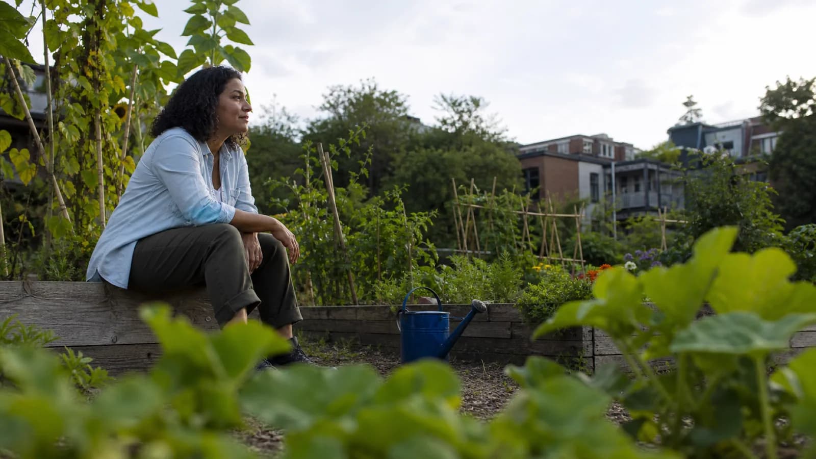 Une femme dans la quarantaine prend une courte pause dans un jardin communautaire montréalais.