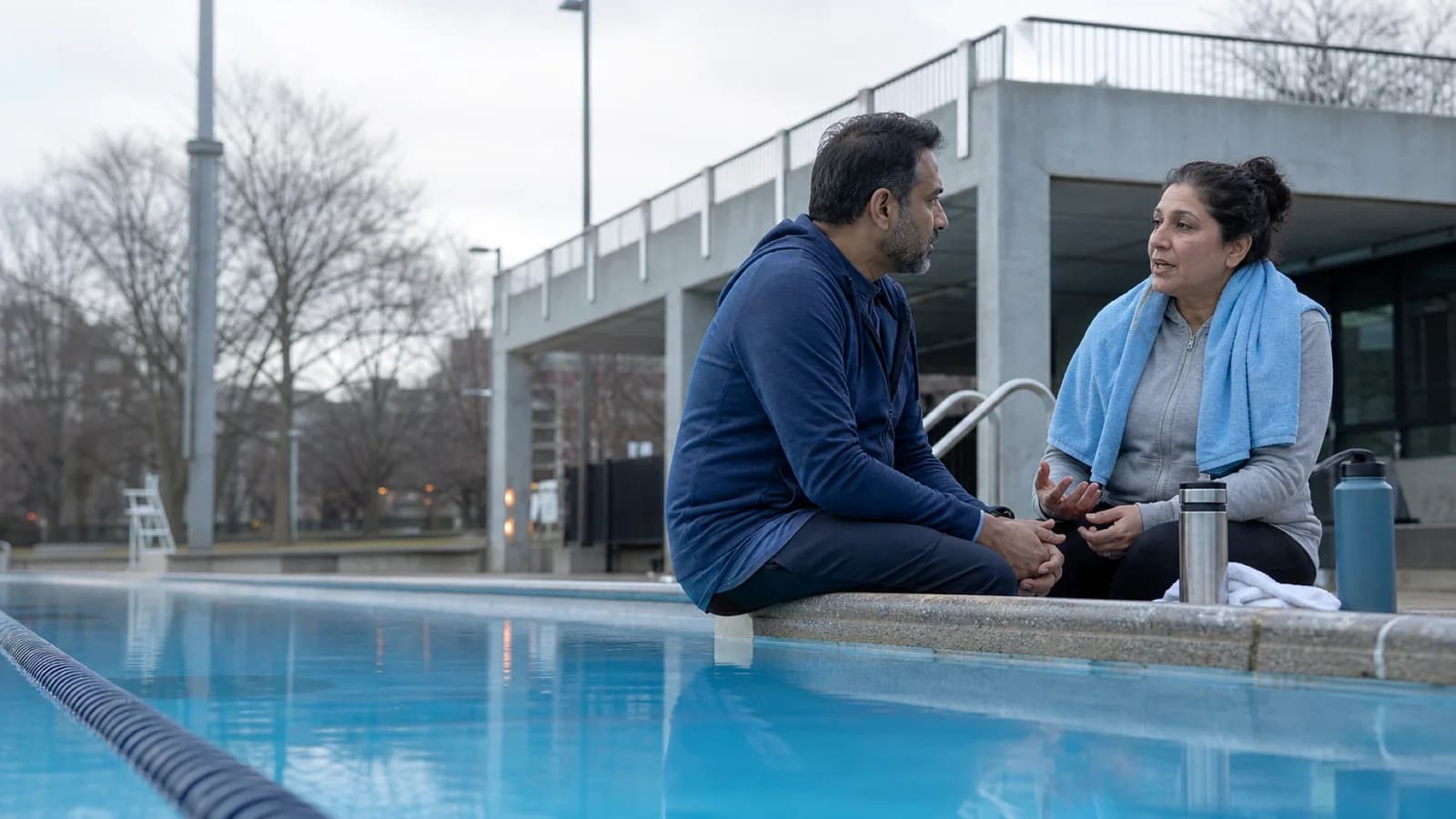 Un frère et une sœur d’âge moyen parlent calmement après une baignade dans une piscine publique torontoise.
