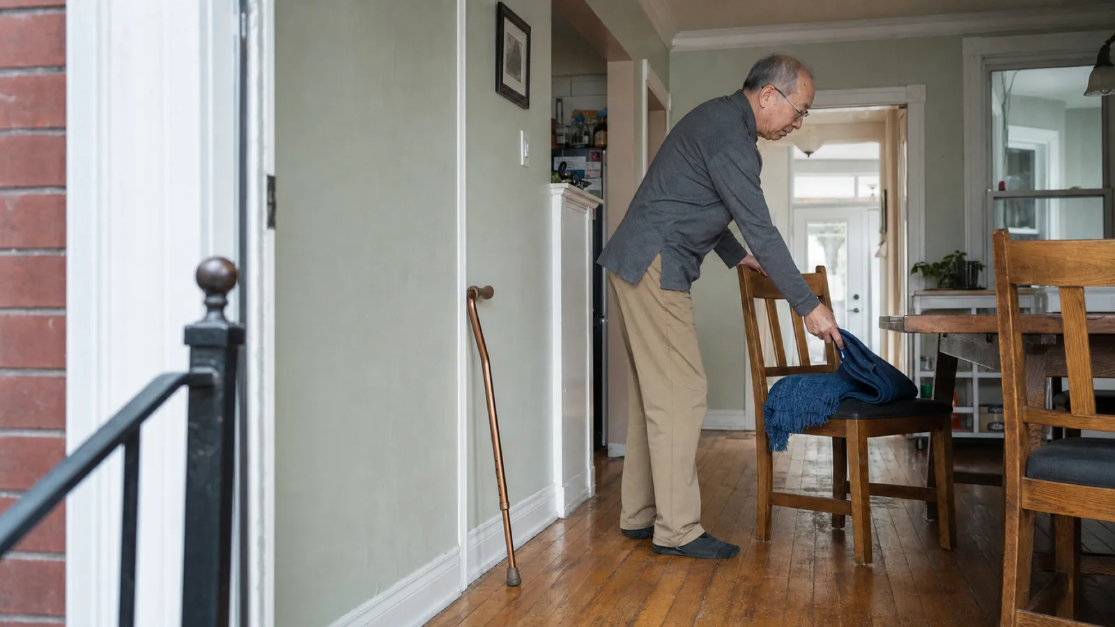 An older Chinese Canadian man prepares a chair and clears the path before an at-home blood collection visit in a Toronto home.